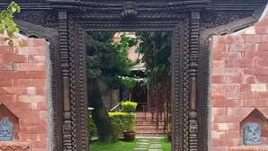 A brick archway leading to a garden with a stone pathway. - Shaligram Hotel (Lalitpur)