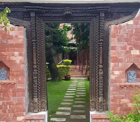 A brick archway leading to a garden with a stone pathway.