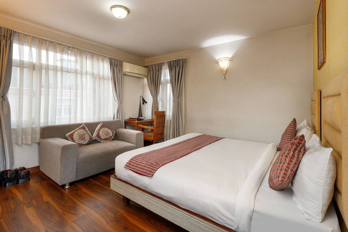 A hotel room with a bed, a sofa, a desk, and a chair.