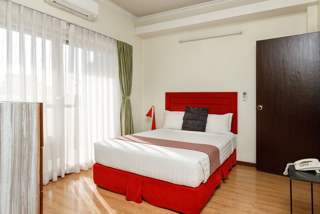 Ein Hotelzimmer mit einem Bett, einem Telefon und einer Tür.