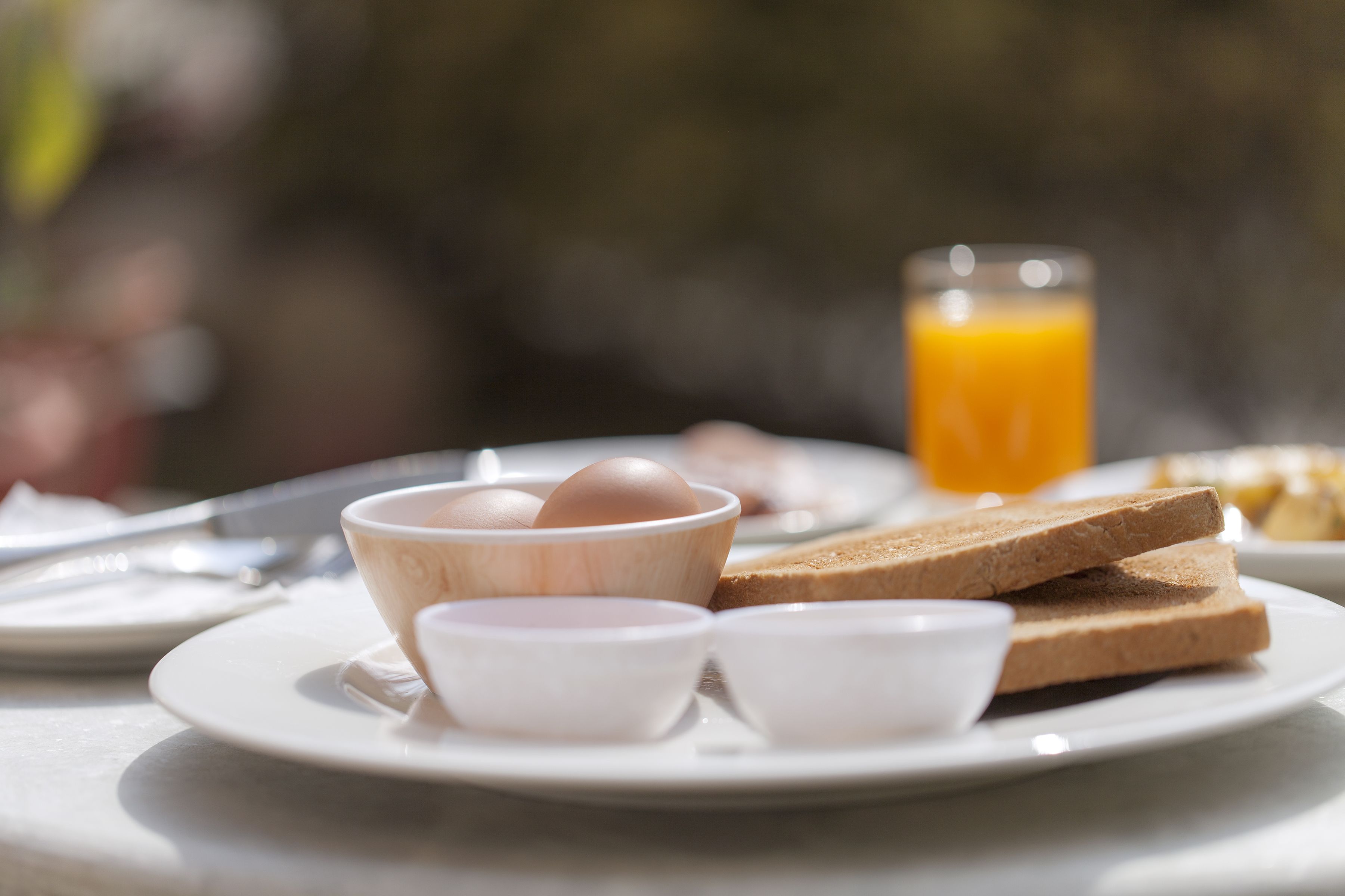 En morgenmadsanretning med æg, ristet brød og appelsinjuice på en tallerken.