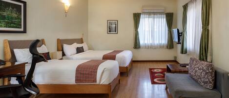 Una habitación de hotel con dos camas, un escritorio, una silla, un sofá y una televisión.