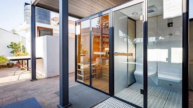 A modern building with a glass door entrance, a wooden ceiling, and a visible interior with a staircase and seating area. - Shaligram Hotel (Lalitpur)