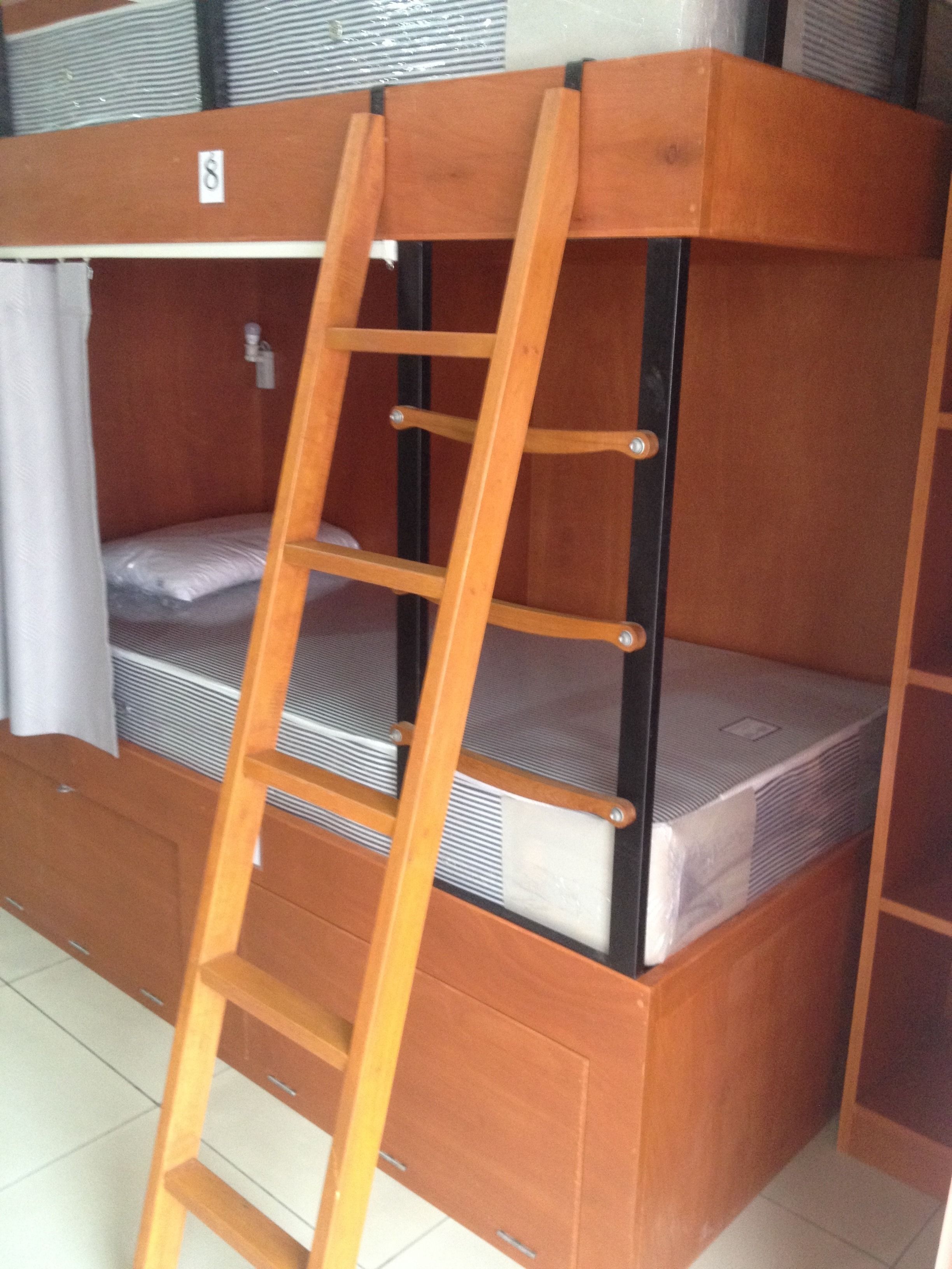 A bunk bed with a wooden ladder, a mattress, and a small shelf.