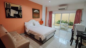 Habitación de hotel con cama, sofá, escritorio y balcón con mesa y sillas.