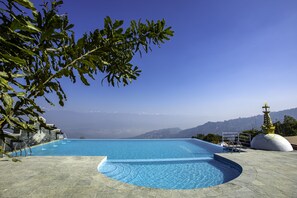 Una piscina con vistas a montañas y un cielo despejado.
