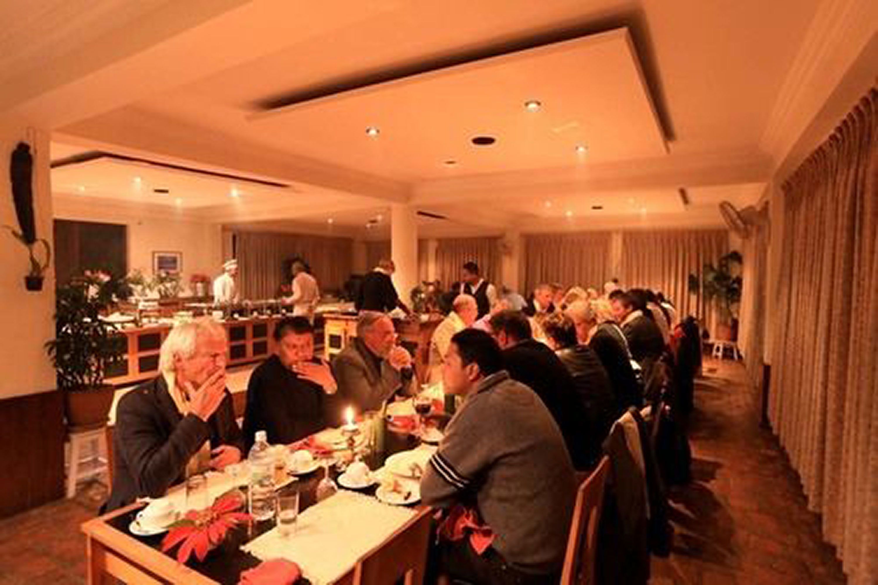 Un comedor formal con varias mesas y comensales sentados.