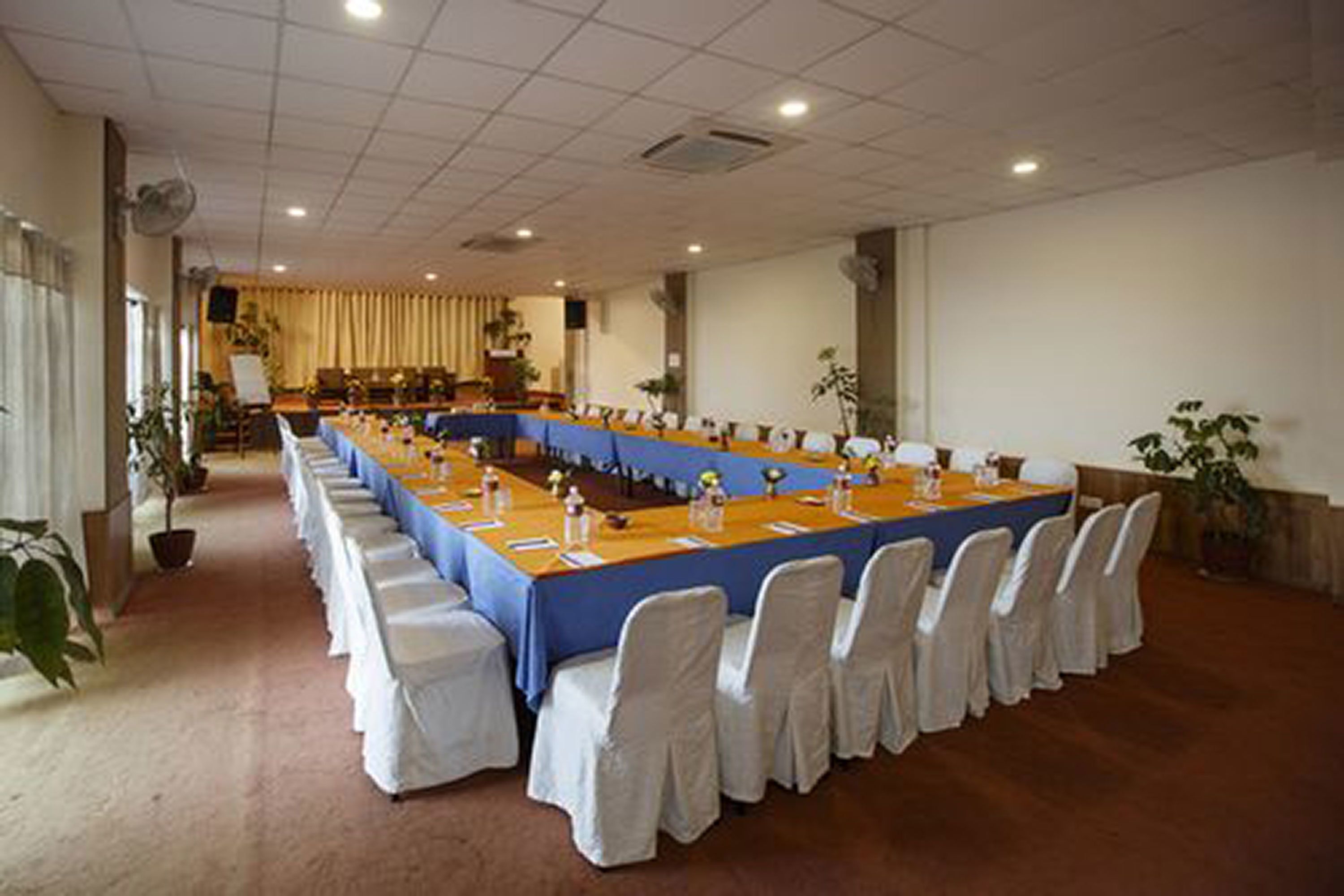 A conference room with a long table, white chairs, and a blue tablecloth.