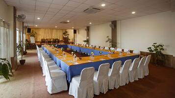 A conference room with a long table, white chairs, and a blue tablecloth.