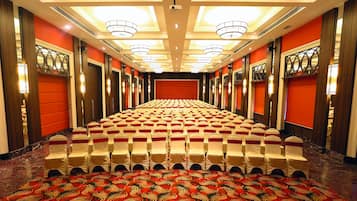 Una sala de conferències d'hotel amb files de cadires, una catifes estampada i una paret vermella.