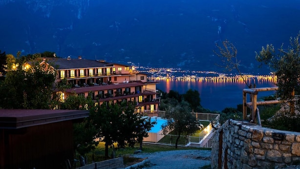 Un hotel con varios pisos, piscina y vista a un lago con muelle.