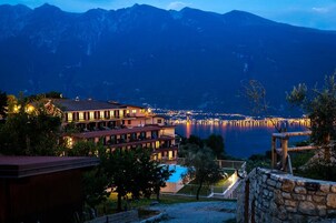 Un hotel con varios pisos, piscina y vista a un lago con muelle.