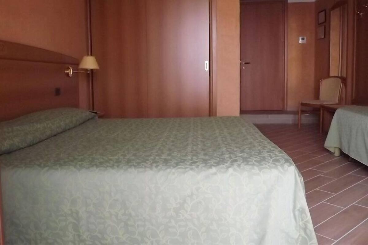 Una habitación con una cama, una silla y una lámpara.