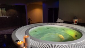 Un jacuzzi con velas, una planta en maceta y un farol en una habitación tenuemente iluminada.