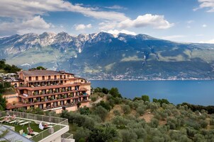 Un hotel de varios pisos con balcones que dan a un lago y montañas.
