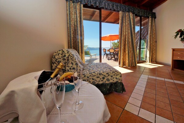 A room with a bed, a dining area with a table and chairs, and a view of the outside. - Park Hotel Zanzanù (Tignale)