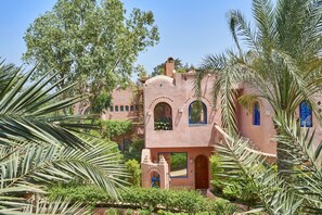 A traditional building with arched windows and a central courtyard surrounded by lush greenery. - Lazib Inn Resort & Spa (Yusuf as-Sidiq)