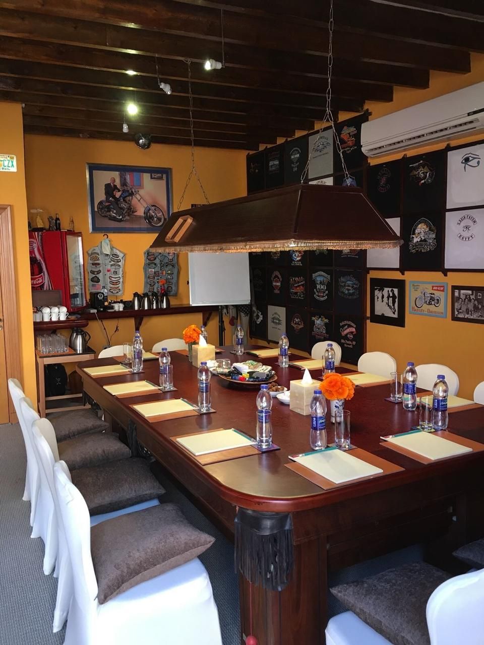 A conference room with a long table, chairs, and a hanging light fixture.
