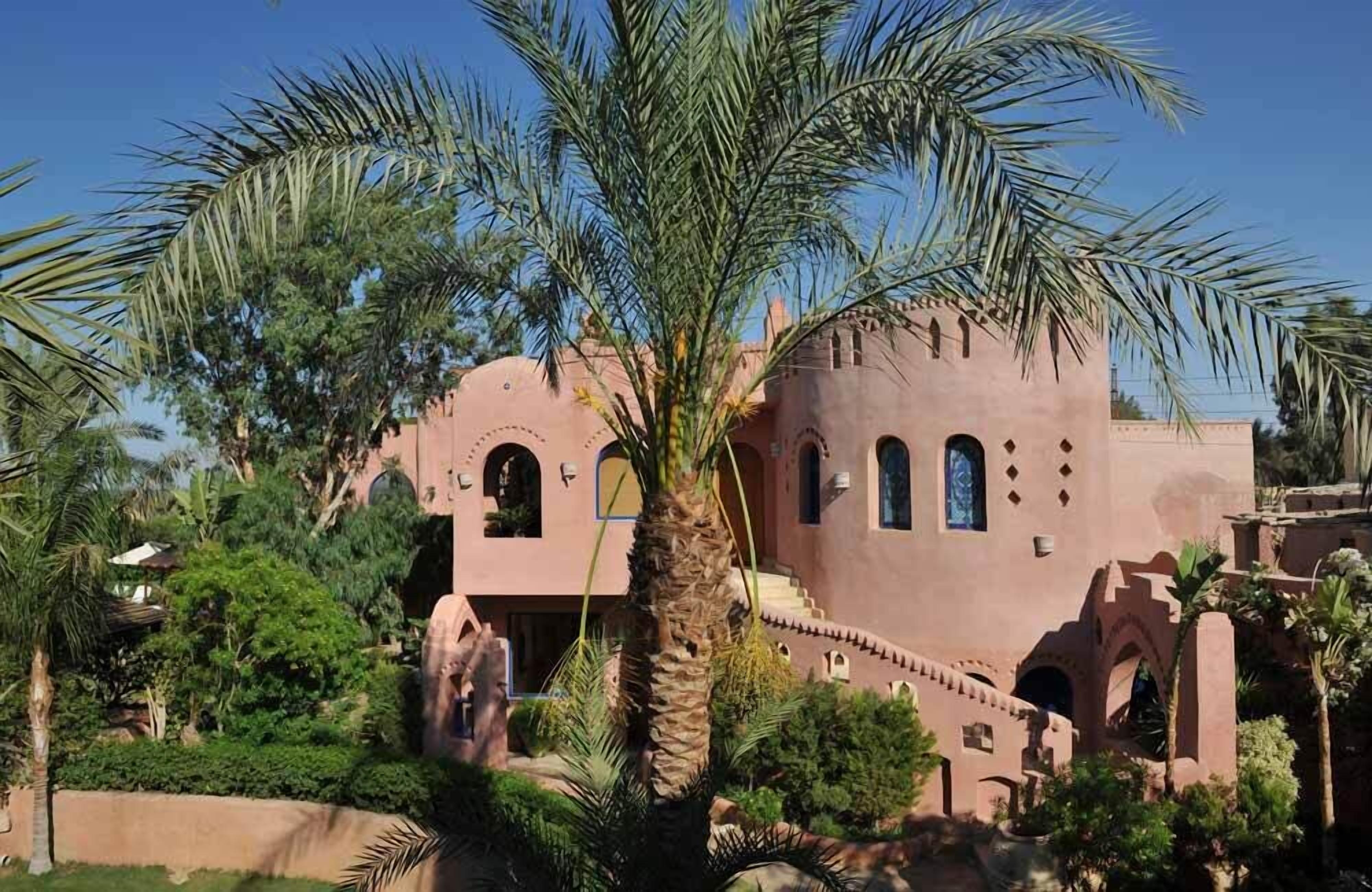 A traditional building with arched windows and a palm tree in the foreground.
