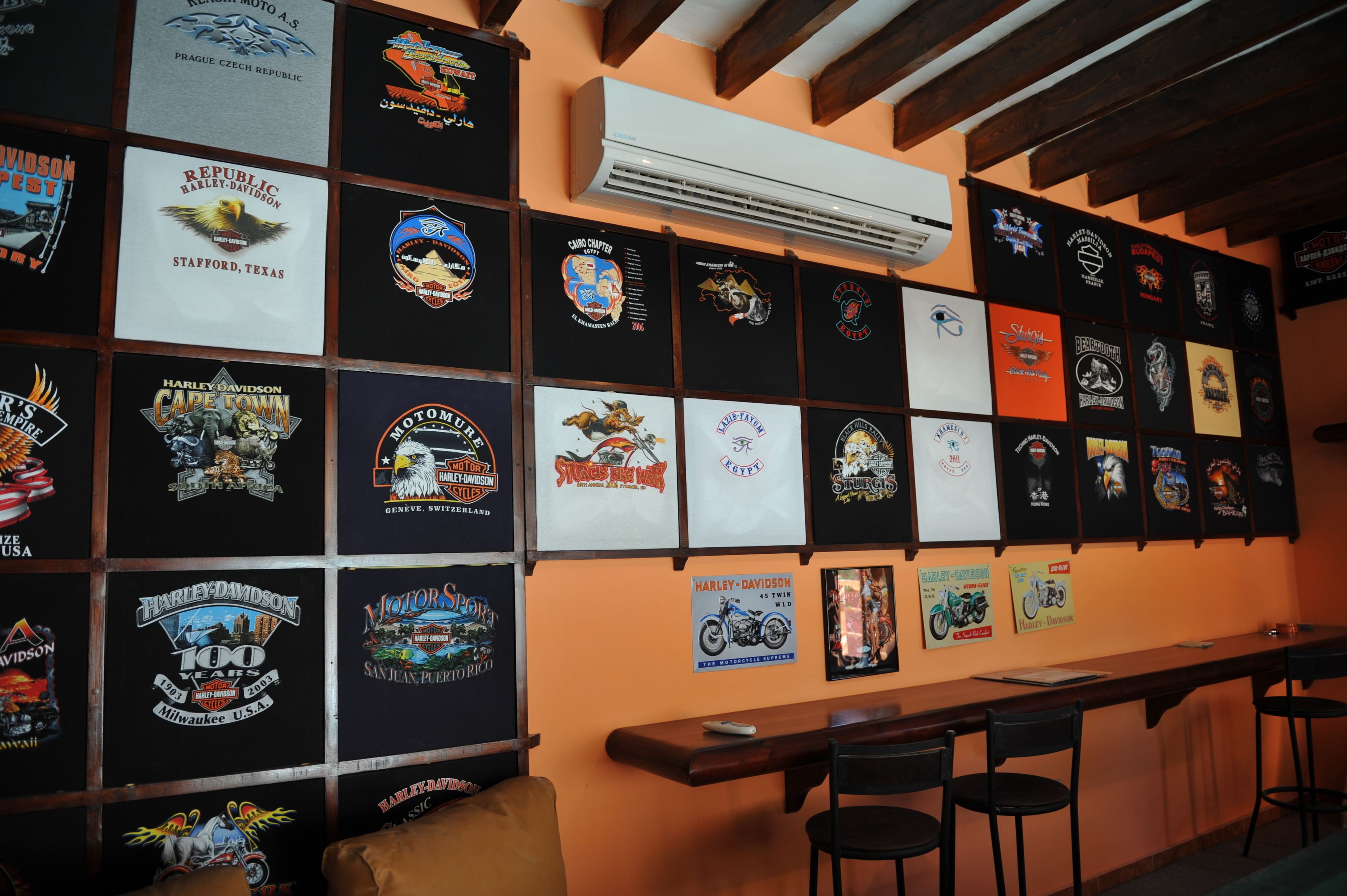 A wall with various motorcycle-themed t-shirts and posters.
