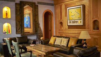 A modern living room with a leather sofa, a glass coffee table, and a wooden accent wall with framed artwork.