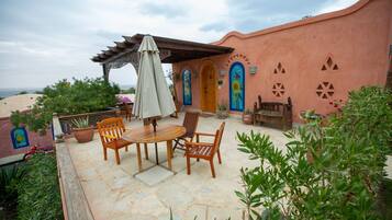 A patio with wooden furniture, a pergola, and a view of the sea.