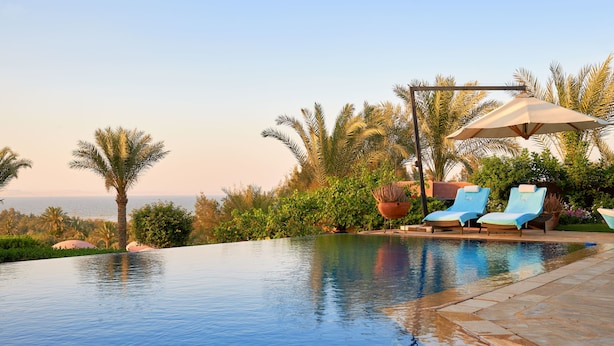 Una piscina amb gandules i vista a l'oceà.