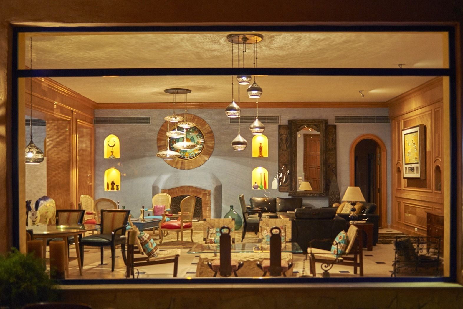 Uma sala de estar bem iluminada com lareira, várias áreas de estar e luminárias decorativas.
