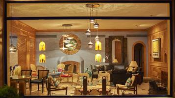 Uma sala de estar bem iluminada com lareira, várias áreas de estar e luminárias decorativas.