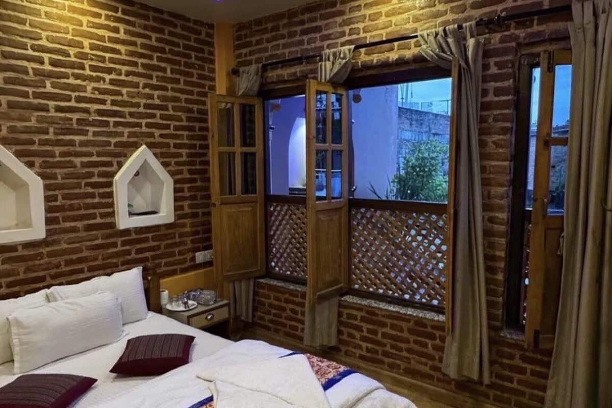Un dormitorio con cama de madera, ventilador de techo y vista por una ventana con cortinas.