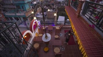 A rooftop terrace with outdoor seating, a decorative lamp, and a view of the cityscape.