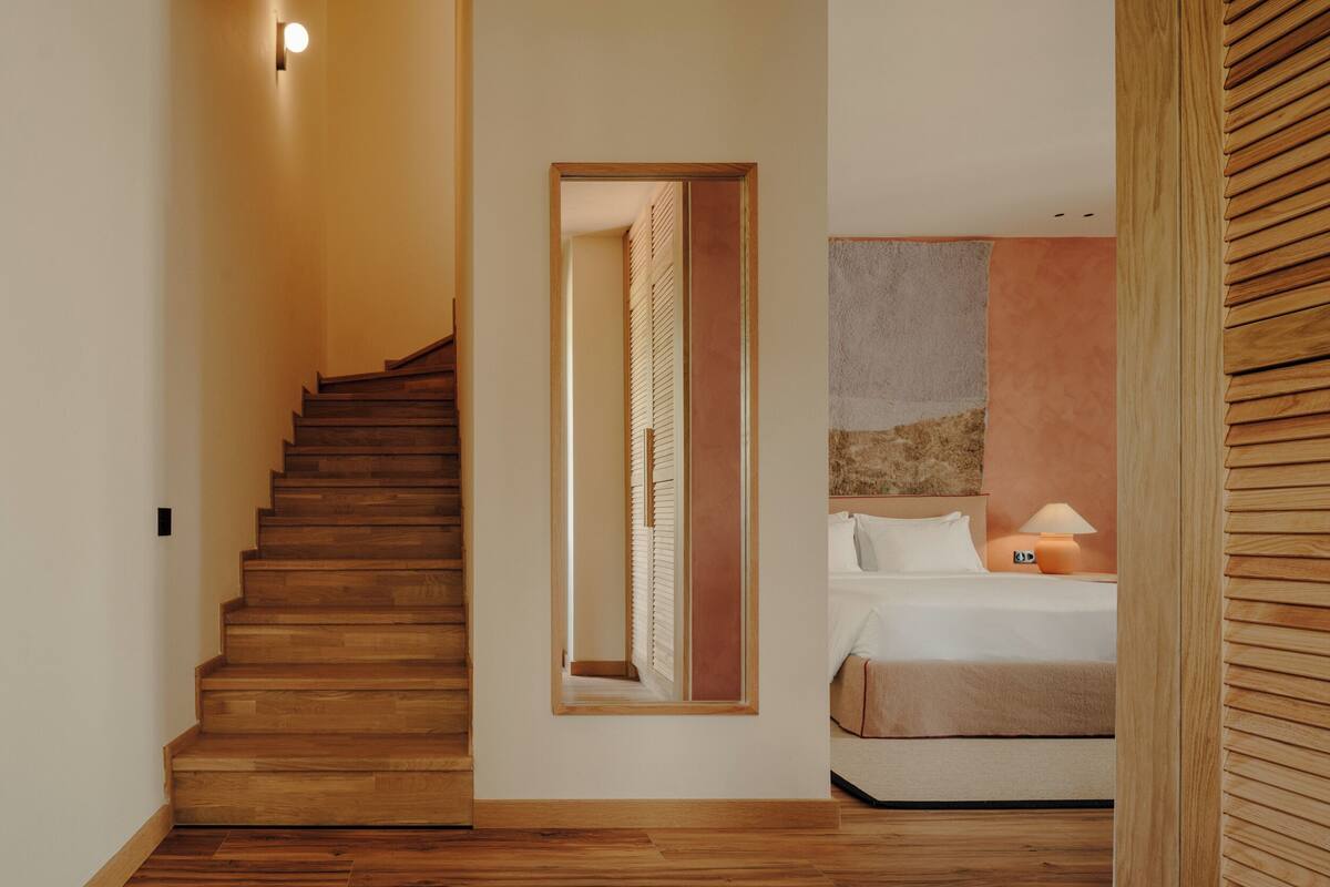 A staircase leading to a bedroom with a bed, a nightstand, and a lamp.