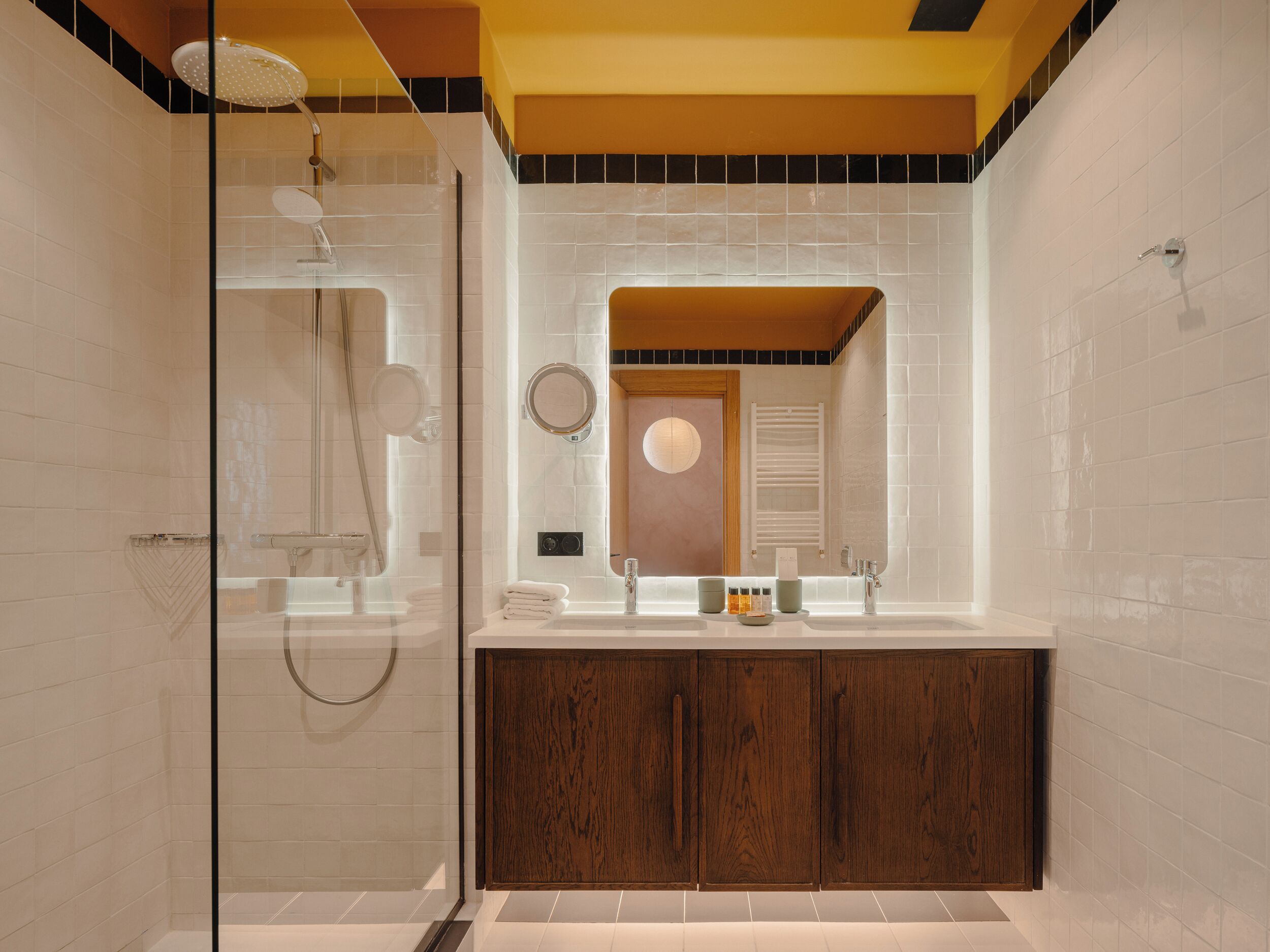 A modern bathroom with a glass shower enclosure, a vanity with a mirror, and wooden cabinets.