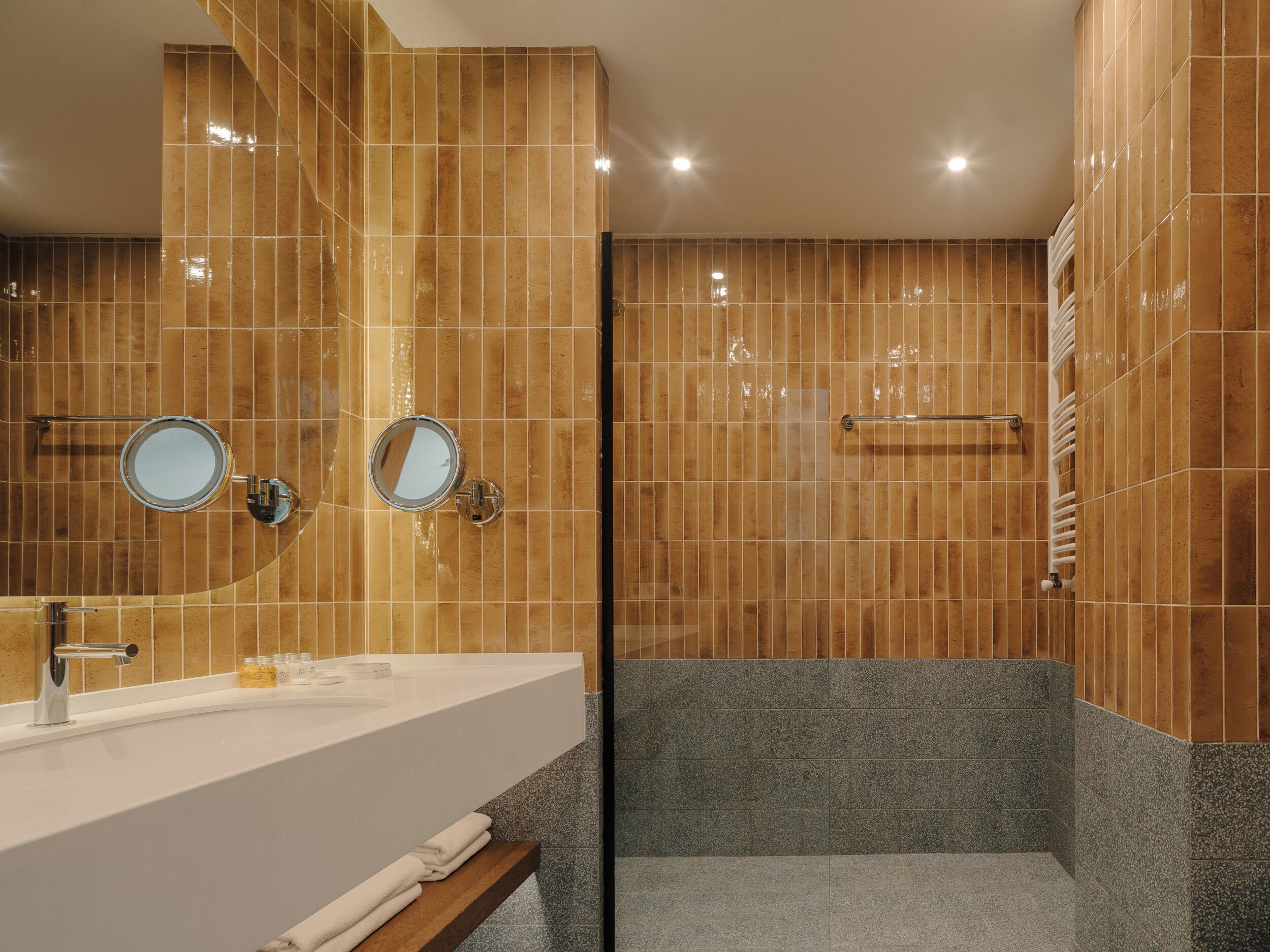Une salle de bain moderne avec un grand lavabo, deux miroirs et un espace douche.
