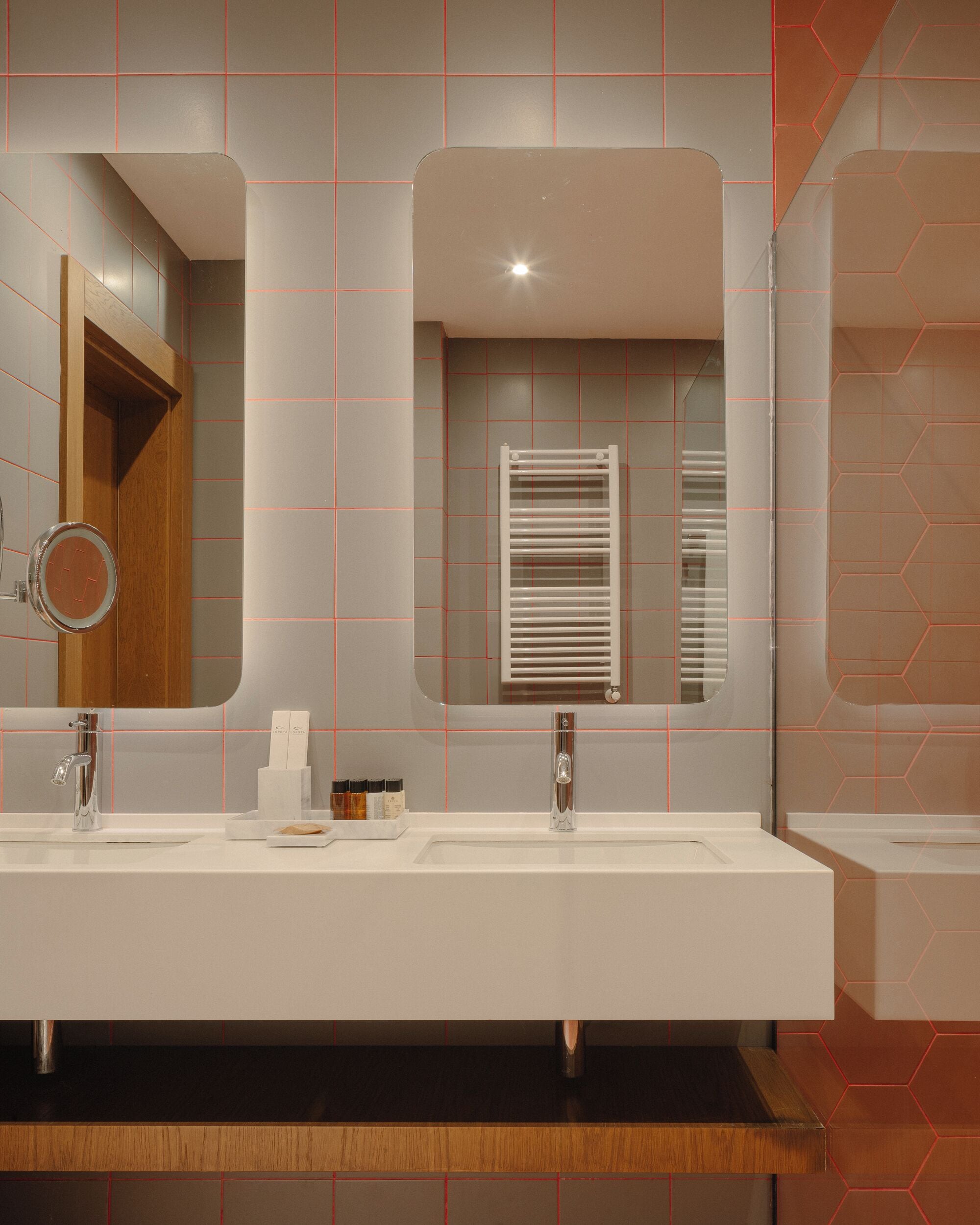 A modern bathroom with two sinks, a mirror, and a towel rack.