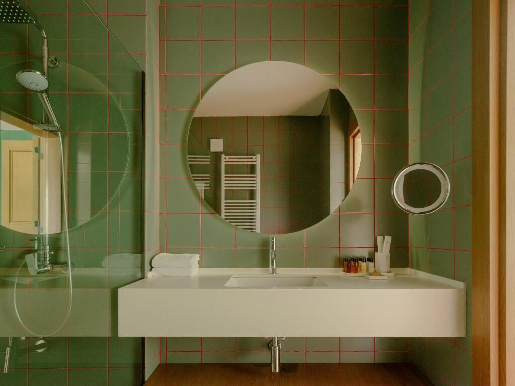 Un baño con lavamanos blanco, un espejo grande y una ducha.