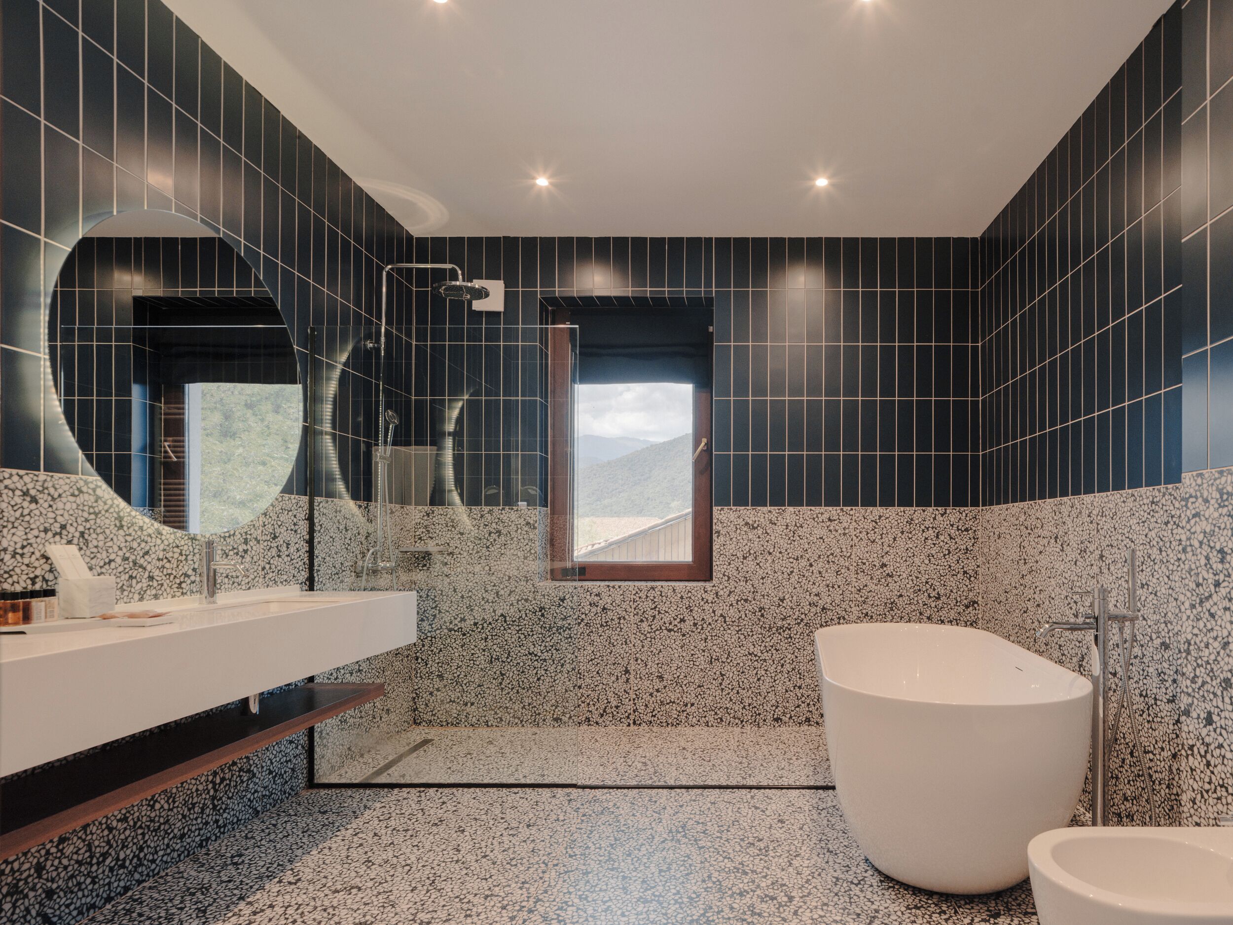 A modern bathroom with a large mirror, a freestanding bathtub, and a shower.