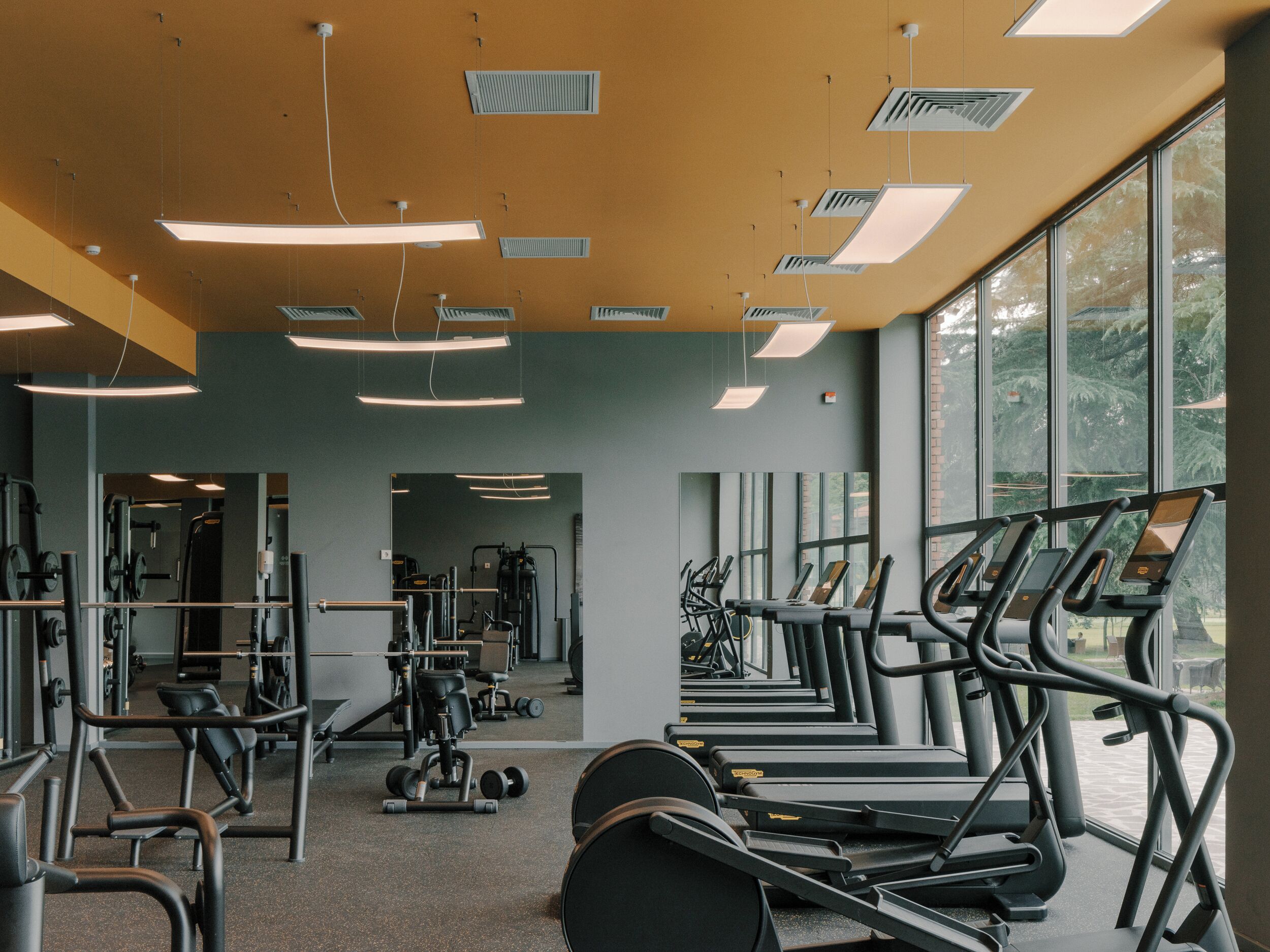 Ein Fitnessstudio mit Laufbändern, Kraftgeräten und Spiegeln.