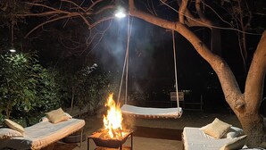 An outdoor seating area with two lounge chairs and a fire pit. - Asiatic Lion Lodge (Mendarda)