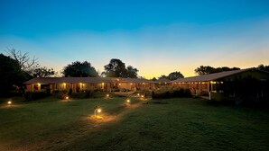 A large, open grassy area with multiple buildings, likely part of a resort or hotel complex. - Asiatic Lion Lodge (Mendarda)