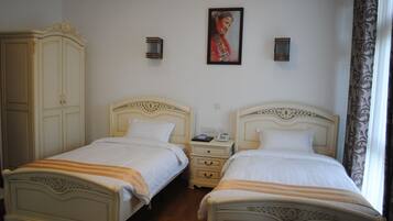 A room with two beds, a wardrobe, a nightstand, and a painting on the wall.