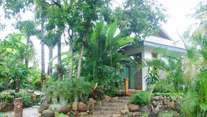 A house surrounded by lush greenery and a stone pathway leading to the entrance. - Myitkyina Plam Spring Resort Hotel (Myitkyina)