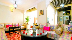 A cozy living room with a sofa set, a round coffee table, and decorative pillows. - Riad Dar Benbrahim (Marrakech)