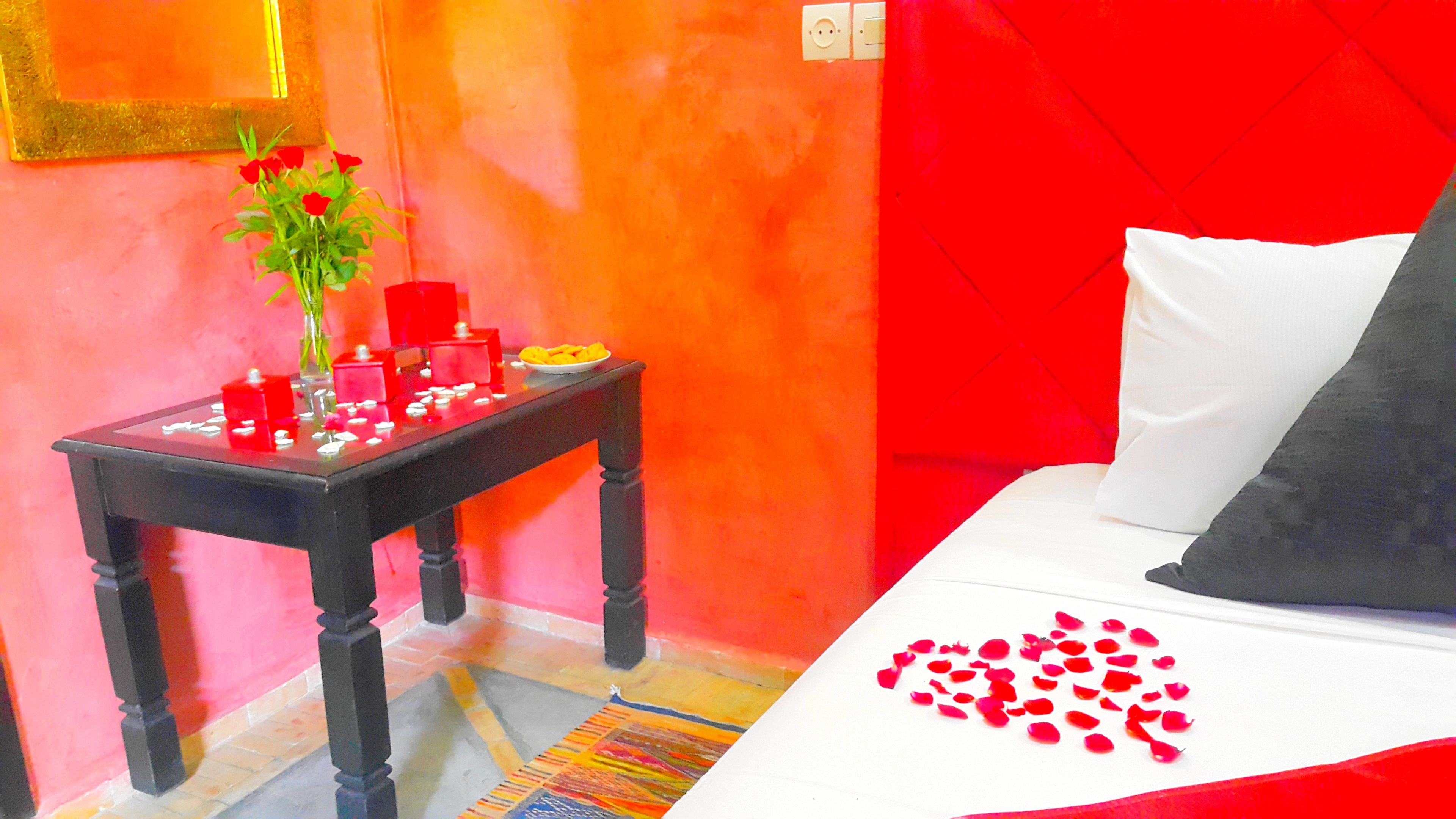 Una habitación con una cama, una mesita con velas y un florero con flores.
