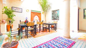 A dining area with a table and chairs, potted plants, and a decorative wall. - Riad Dar Benbrahim (Marrakech)