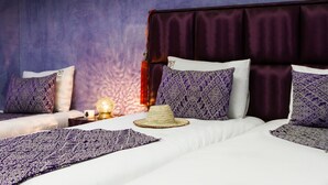 A hotel room with a large bed, multiple pillows, a nightstand with a lamp, and a decorative wall. - Riad Dar Benbrahim (Marrakech)