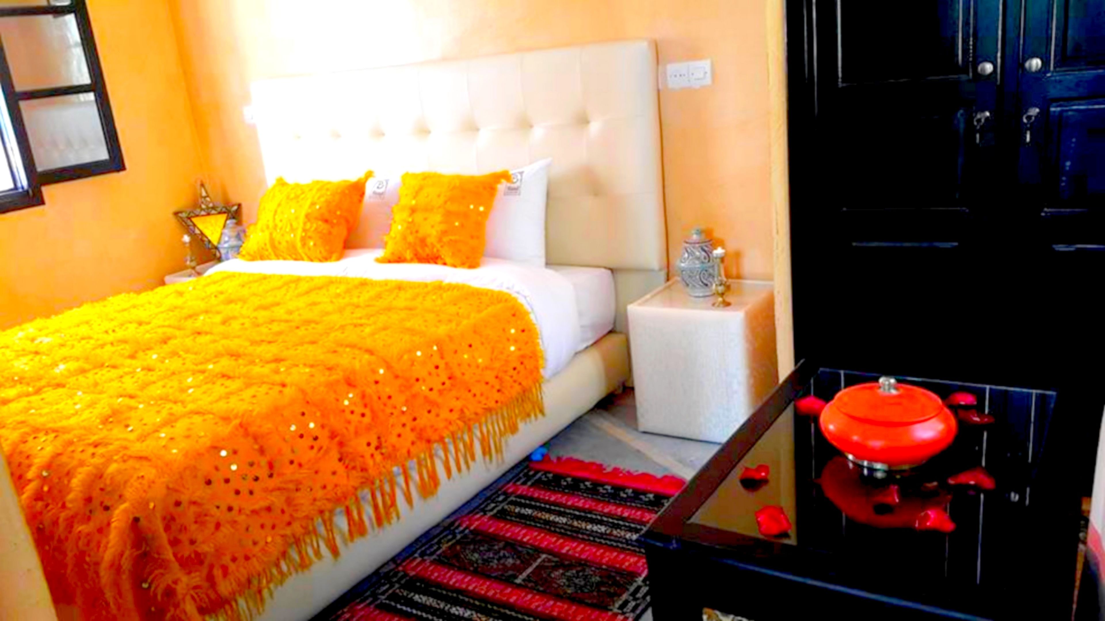 Une chambre d’hôtel avec un grand lit, une table de chevet, une lampe rouge et une armoire noire.
