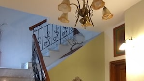 A staircase with a wooden handrail and black metal balusters, leading to a landing with a decorative mirror and a small shelf with items. - Guesthouse Papagiannopoulou (Zagora-Mouresi)