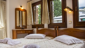 A room with two beds, a wooden dresser, a mirror, and a window with curtains. - Guesthouse Papagiannopoulou (Zagora-Mouresi)