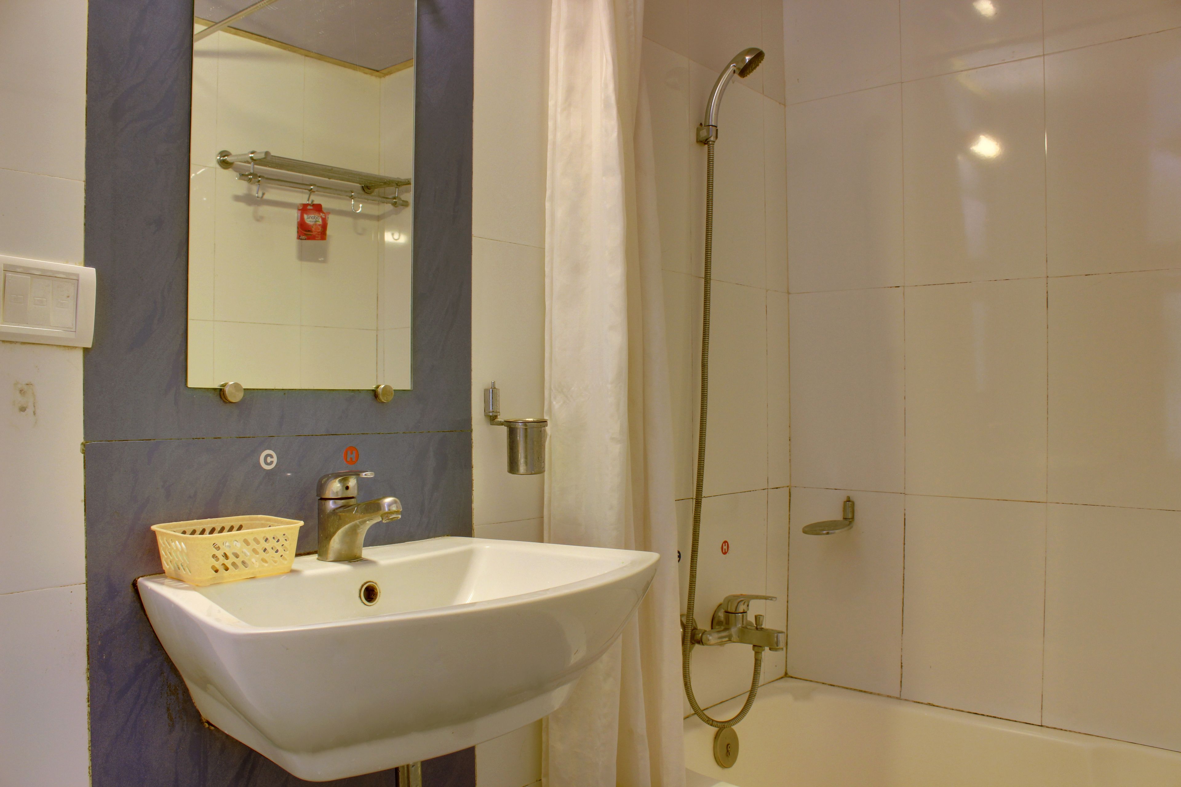 Un baño con lavamanos blanco, espejo, ducha y toallero.